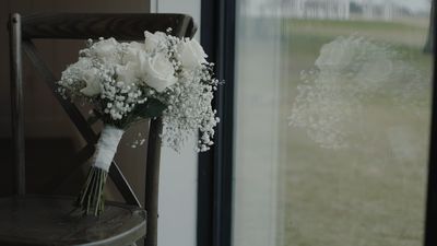 Bridal bouquet on a cross-back chair in window light