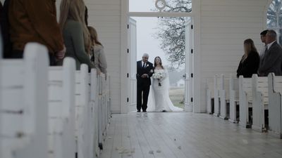 Bride and father walking down the aisle of a white Texas chapel