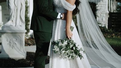 Bride and groom with bouquet, emerald suit and veil