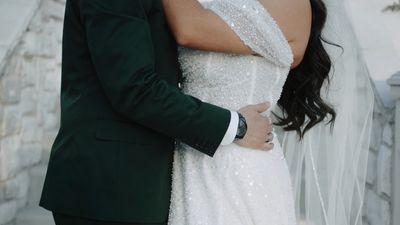Bride in beaded gown, groom in emerald suit, detail