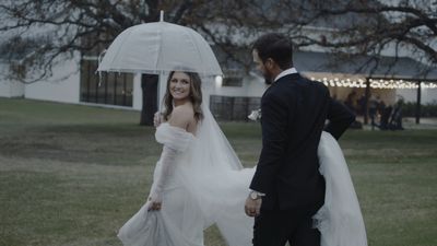Bride and groom walking under an umbrella in the rain