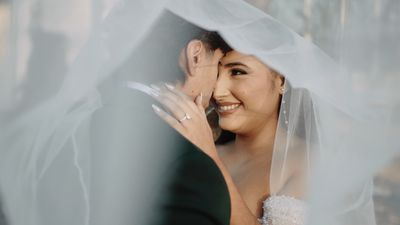 Bride and groom under flowing veil, cinematic light