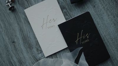 His and her vow books on dark wood beside cufflinks
