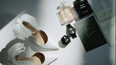 Wedding details flatlay with shoes, perfume, and invitation