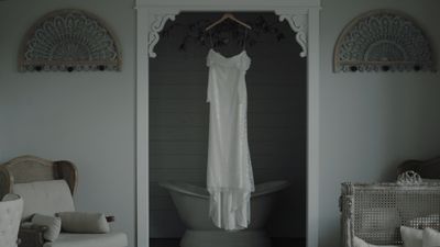 Wedding dress hanging beside a clawfoot tub in the bridal suite