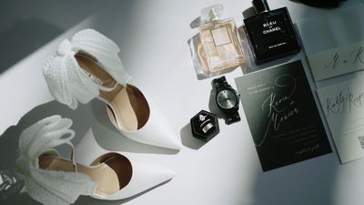 Bridal flatlay with rings, invitation, shoes, and cologne