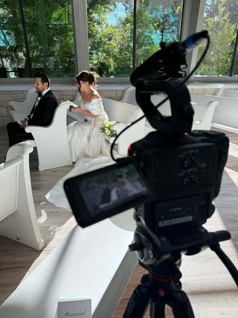 Wesley Blalock filming a bride and groom seated in a chapel with reserved sign